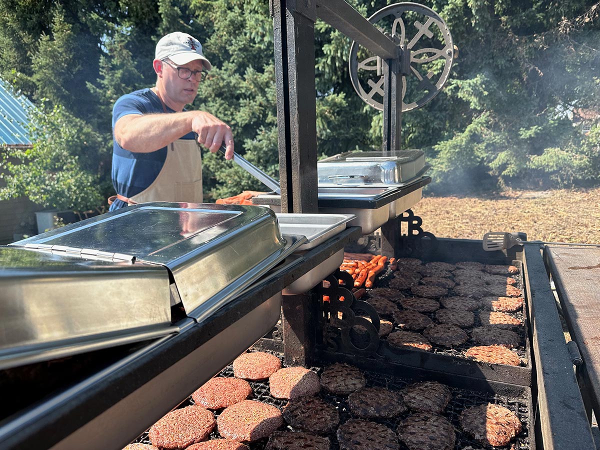 Man grilling lots of burgers and hotdogs